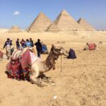 The Great Pyramids of Giza with a camel and some locals in the foreground