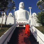 A monk walks upstairs towards the Sri Maha Bodhi Viharaya Buddha statue in Kandy, Sri Lanka