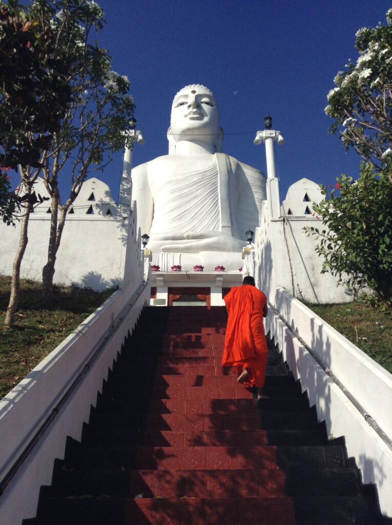 A monk walks upstairs towards the Sri Maha Bodhi Viharaya Buddha statue in Kandy, Sri Lanka