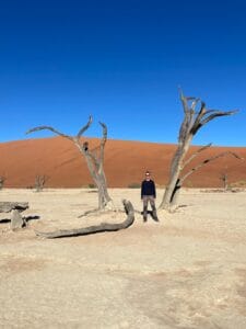Alex standing between scroched trees at Deadvlei in the Namib Desert, Namibia.