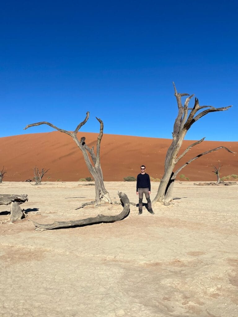 Alex standing between scroched trees at Deadvlei in the Namib Desert, Namibia.