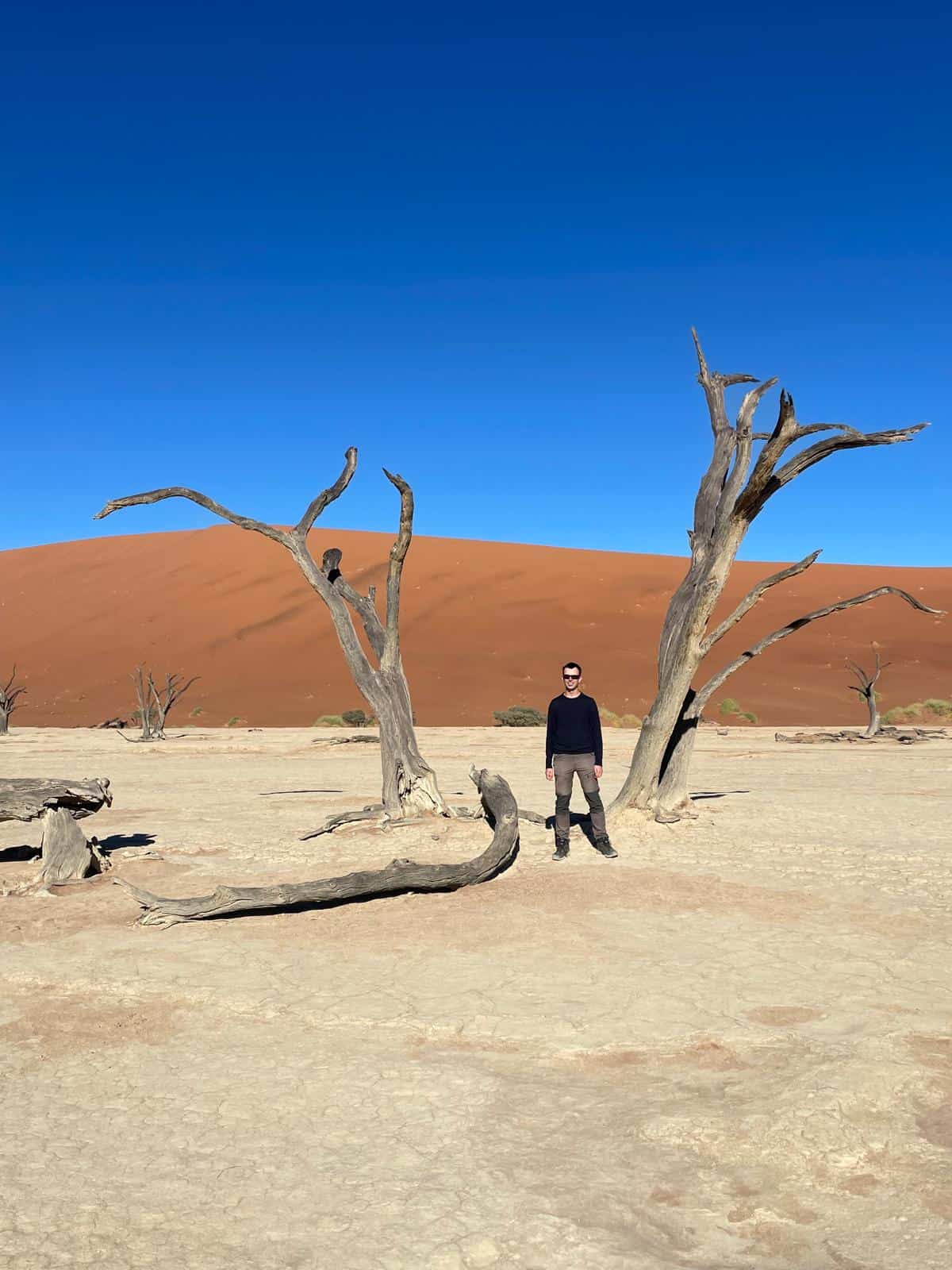 Alex standing between scroched trees at Deadvlei in the Namib Desert, Namibia.