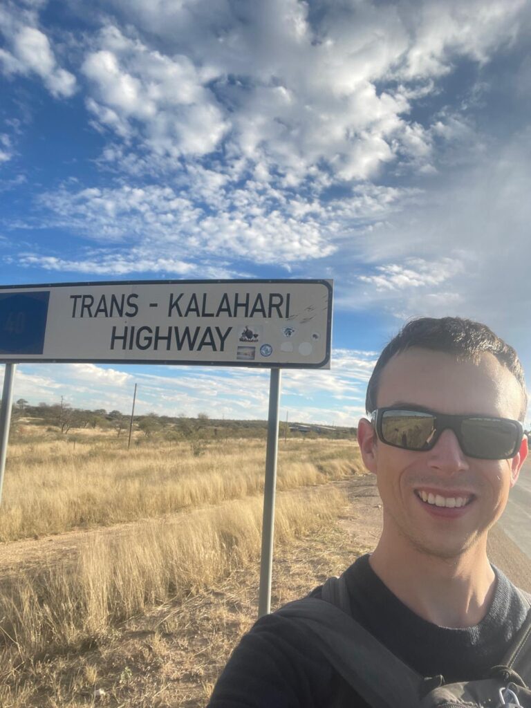 Alex by the Trans-Kalahari Highway sign, just a couple of minutes away from East Gate Rest Camp.
