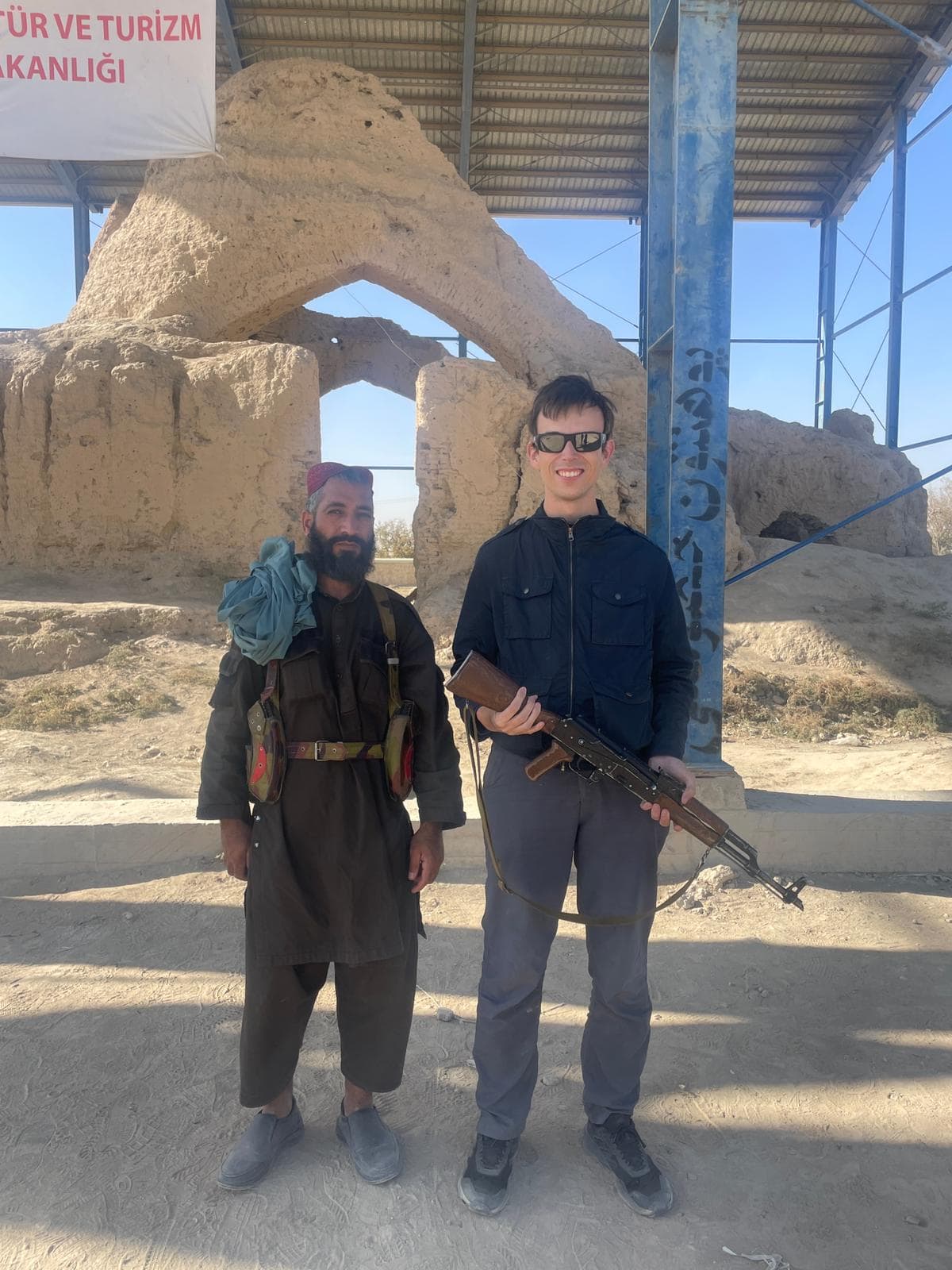 Alex standing alongside a Taliban bodyguard whilst holding his gun in Balkh, Afghanistan.