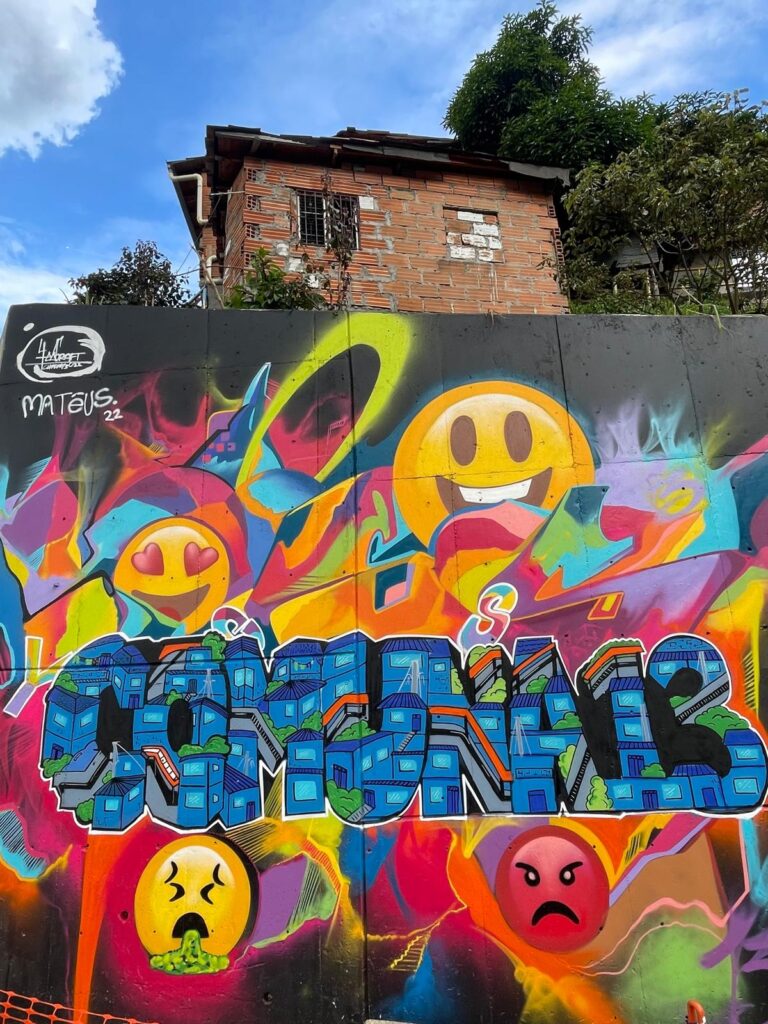 A colourful graffiti wall with the words "Comuna 13" surrounded by emoji images in Medellin's Comuna 13 neighbourhood.