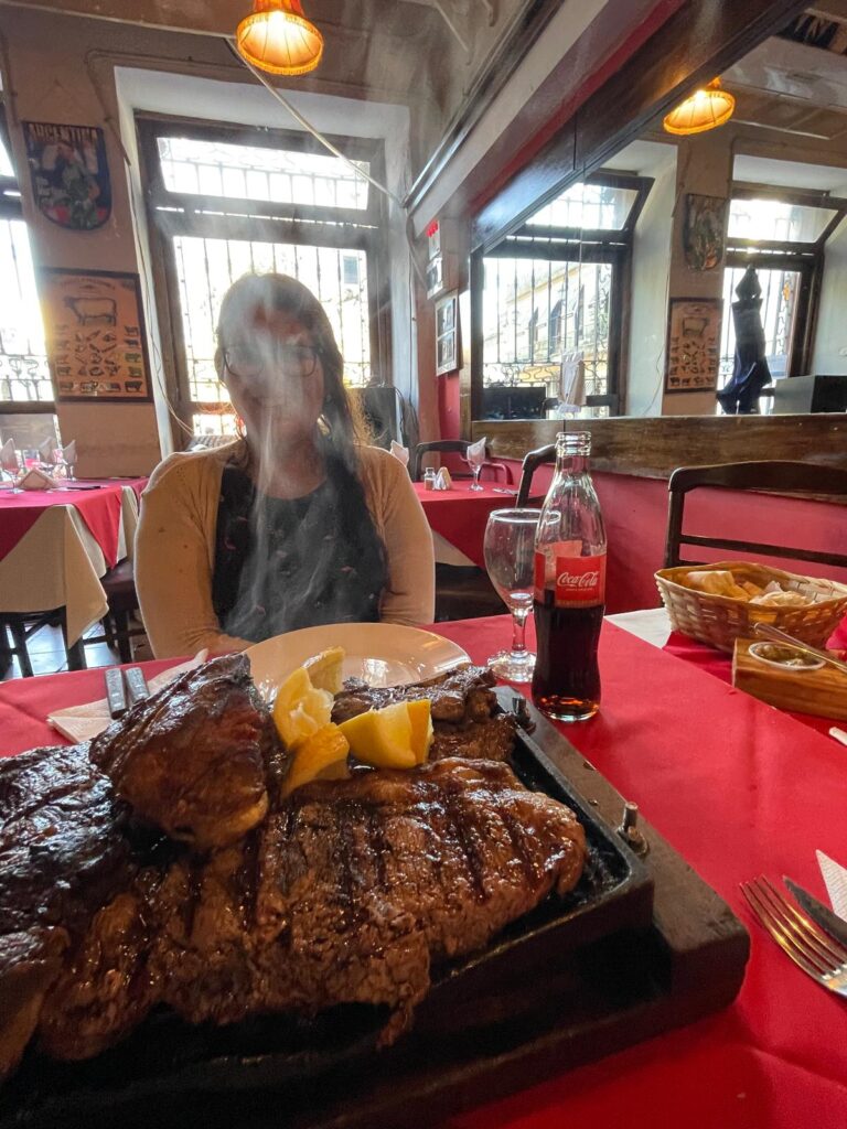 My girlfriend sitting with a big smile on her face as she sees the delicious parrilla that just arrived at our table in San Telmo, Buenos Aires, Argentina.