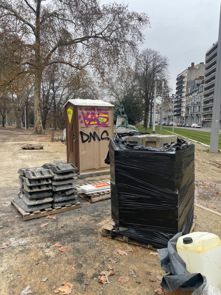 A graffiti-covered portable toilet and discarded building materials in Liege, Belgium.
