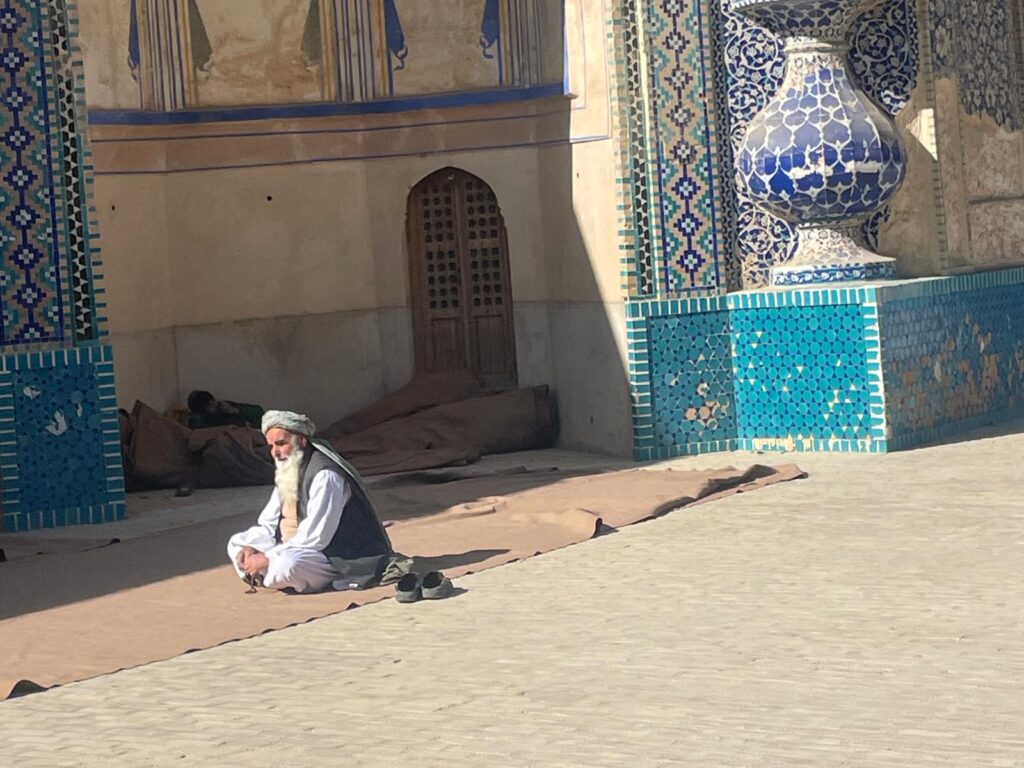 A man kneeling outside the Green Mosque in Balkh, Afghanistan.