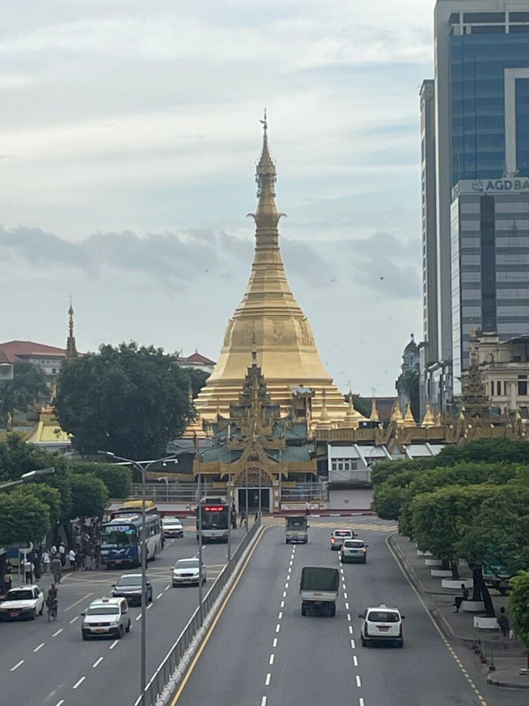 The gold stupa of Sule Pagoda rising above several lanes of vehicles in Yangon, Myanmar.