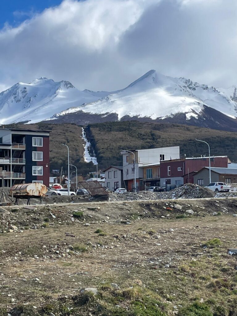 Some buildings in Ushuaia, Argentina, the safest South American city, with snowy mountains in the background.