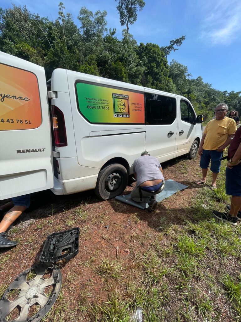 The driver fixes a tyre on his van after it burst on the road between Cayenne and Saint-Georges in French Guiana