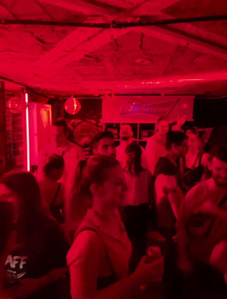 People dancing under red lighting in Vintrash, a popular nightclub in Medellin's Provenza area.