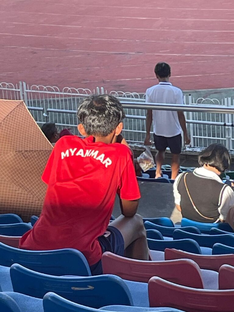 A young fan watches his team whilst proudly showing support for his country