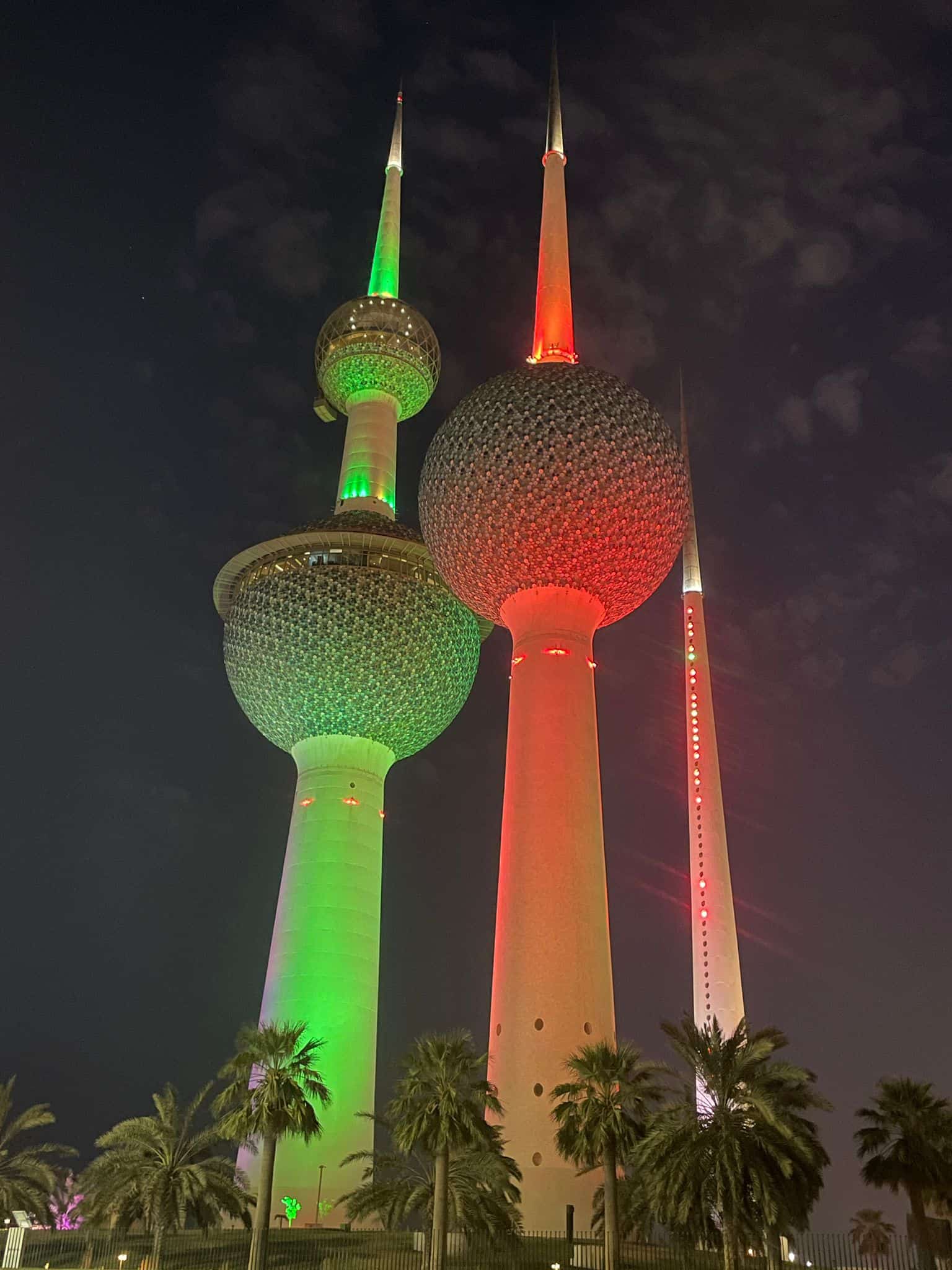 The Kuwait Towers at night in red and green colours in Kuwait City.