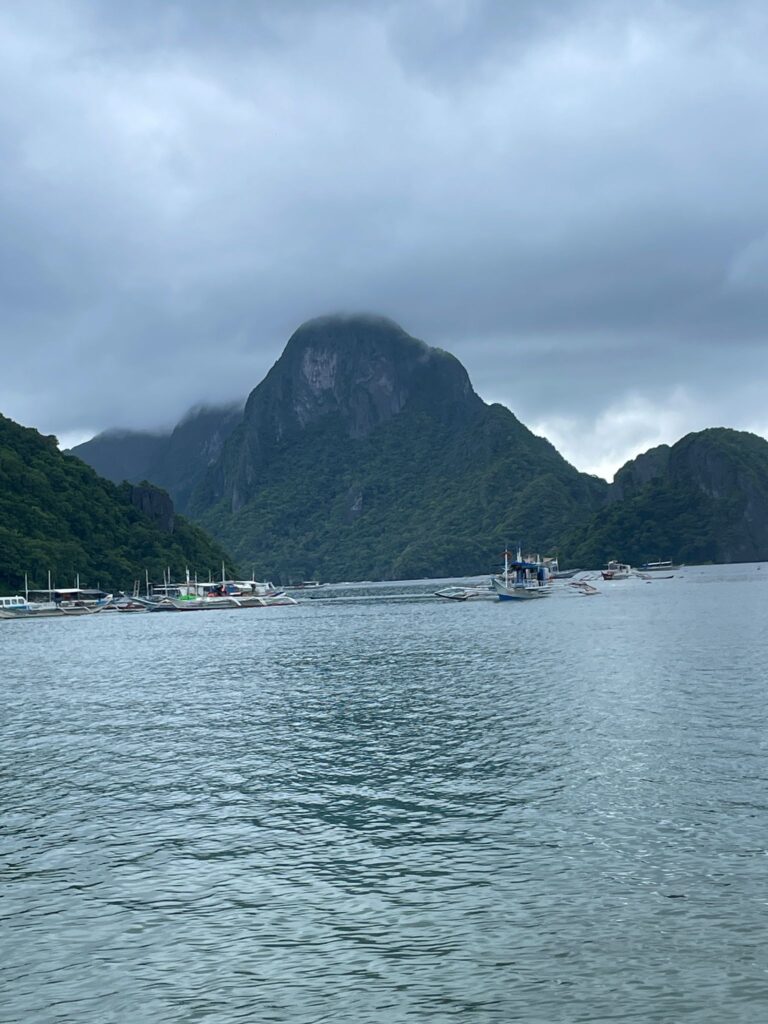 Gloomy El Nido in the Philippines. You can see the cloudy grey skies above the dull-coloured ocean with rocks protruding out of it in the background