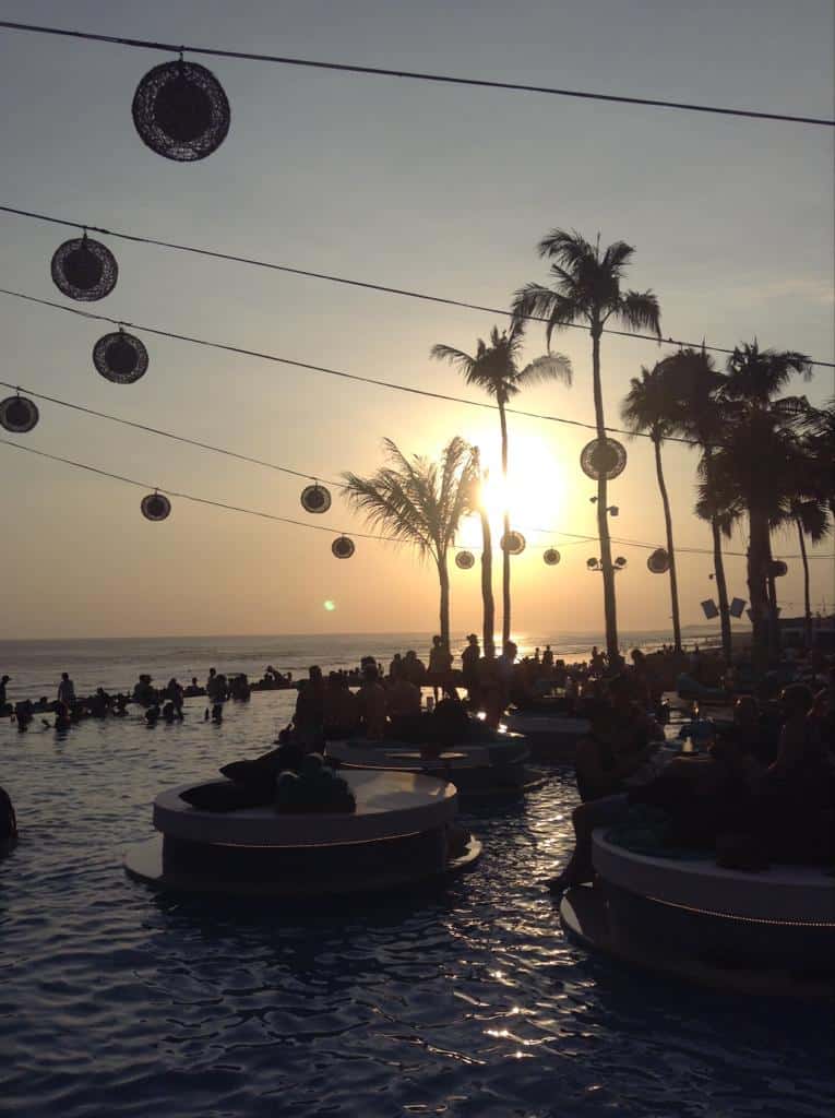 Finns Beach Club in Bali, with the sun setting in the background over the pool