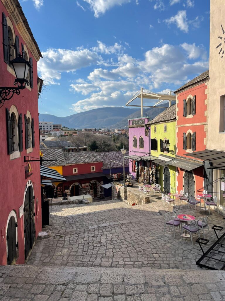 Colourful buildings in Mostar, Bosnia Herzegovina, with the mountains in the background just beneath the bright blue skies
