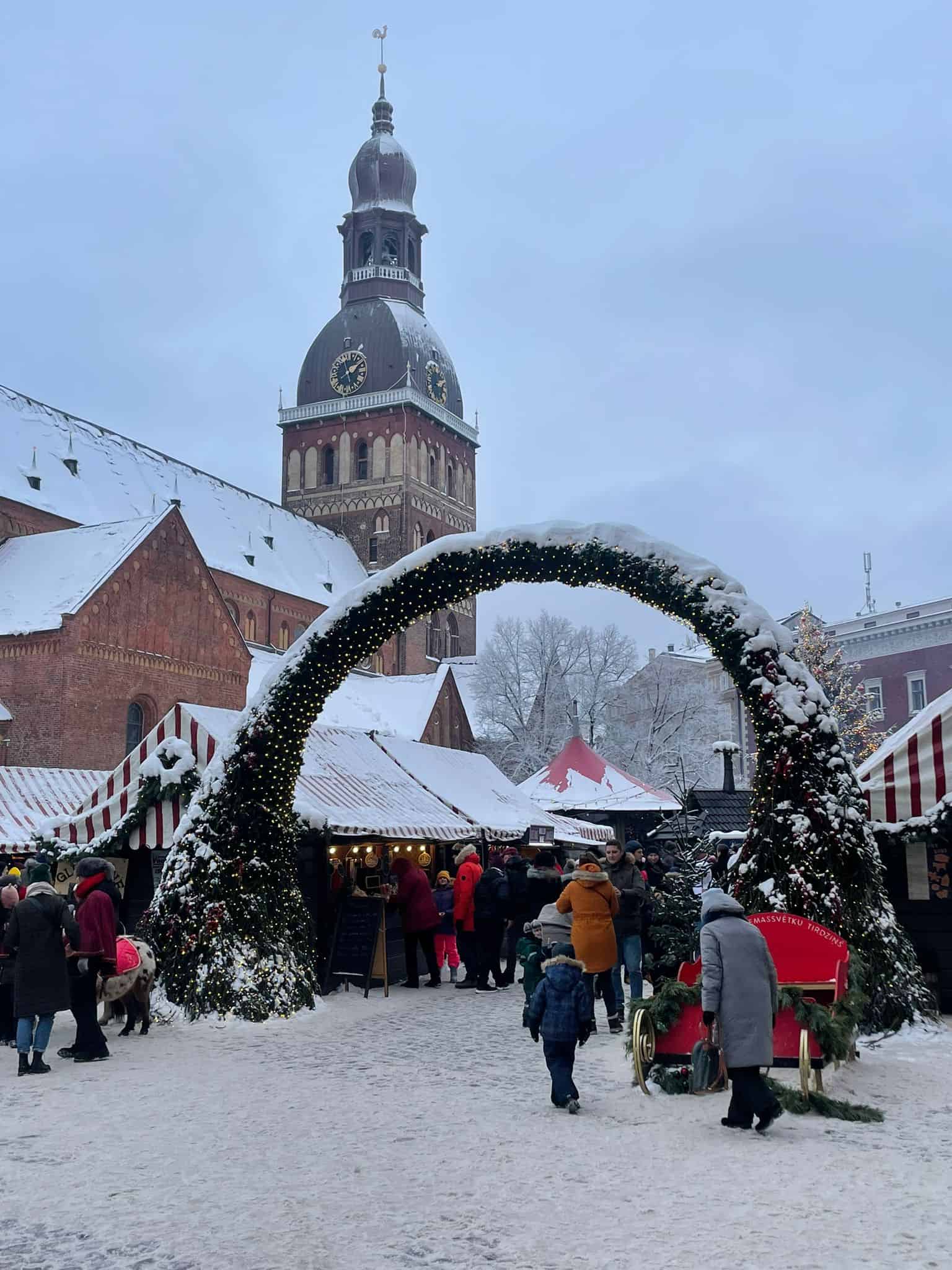 Christmas markets in central Riga with an arch standing over the entrance and snow on surrounding buildings