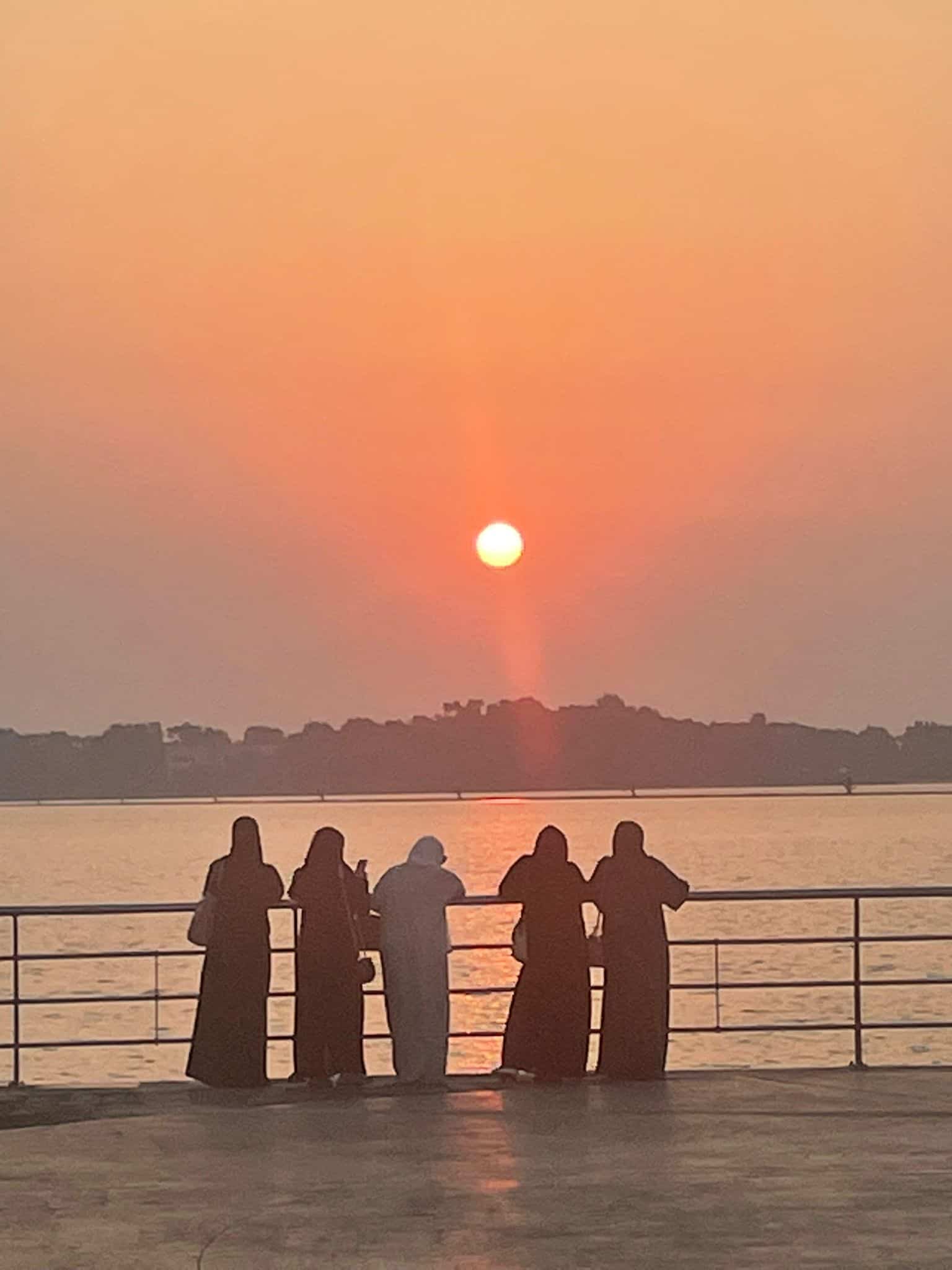 Saudi ladies in Jeddah wearing traditional local attire whilst watching the sun set over the Red Sea