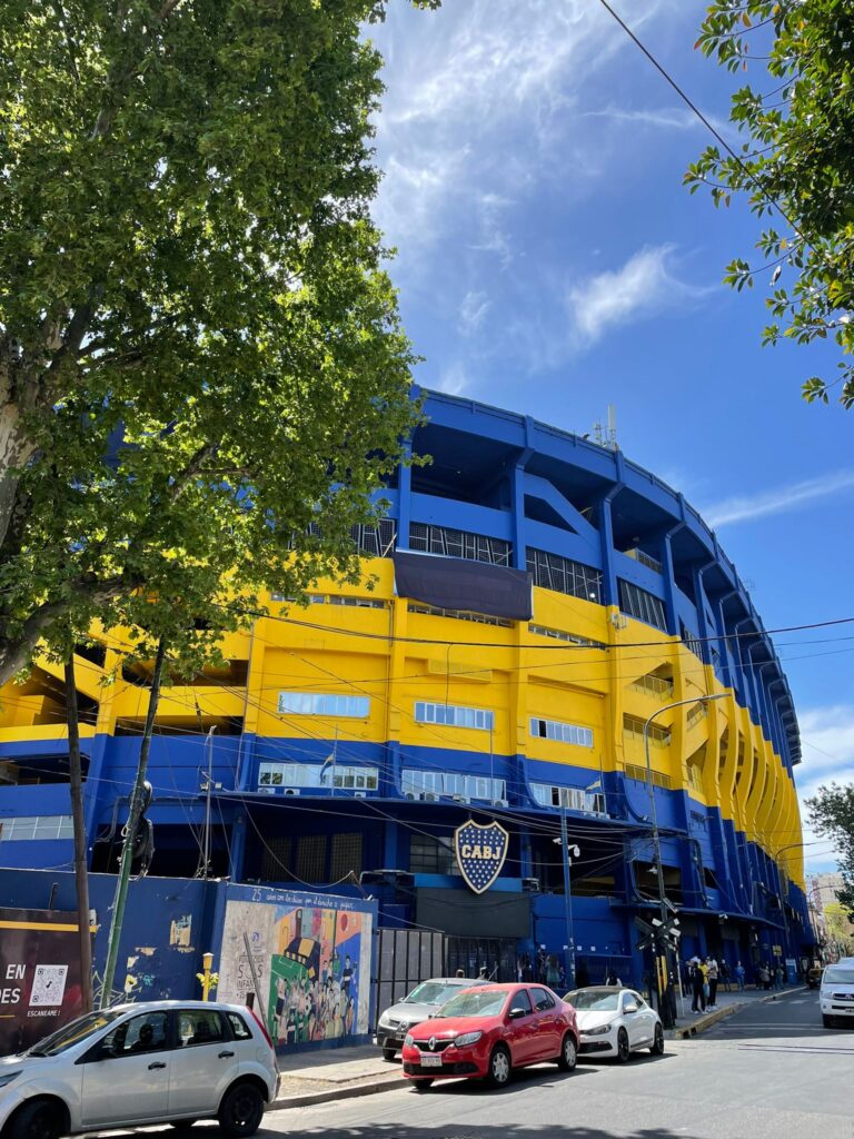 The entrance to the Boca Juniors Museum at the Boca Juniors football stadium: La Bombonera. Several cars are parked outside and the logo is displayed prominently above the entrance