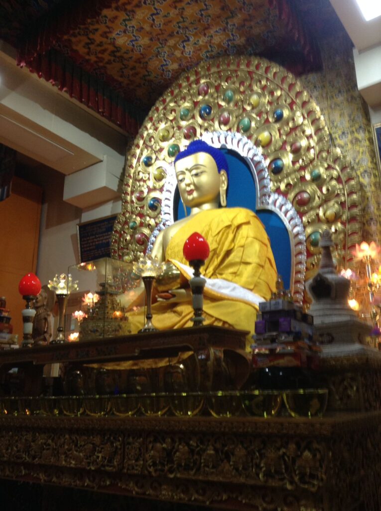A golden statue of Buddha in a gold-coloured robe sitting upon a throne