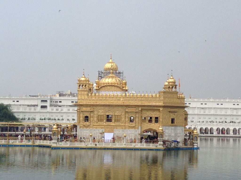 The gold-plated Golden Temple of Amritsar. This picture shows the central sanctum which is surrounded by water, with a long queue of worshippers waiting to enter