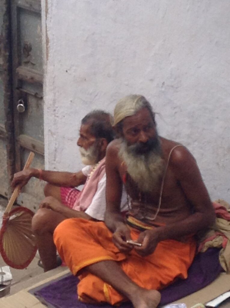 A topless sadhu with orange trunks, sitting on the streets of Varanasi in India