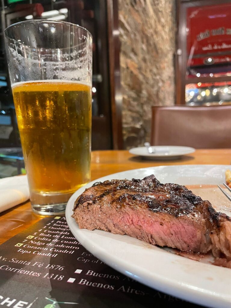 A slightly pink "cocido" steak alongside a beer at a restaurant in Buenos Aires