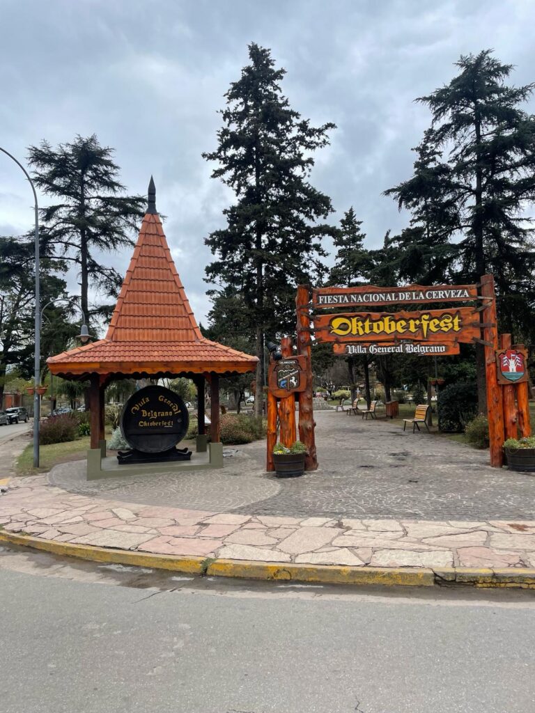 An arch that says "Fiesta Nacional de la Cerveza - Oktoberfest Villa General Belgrano" to mark where the event used to be held. Alongside it is a giant beer barrel with the village's name written on it