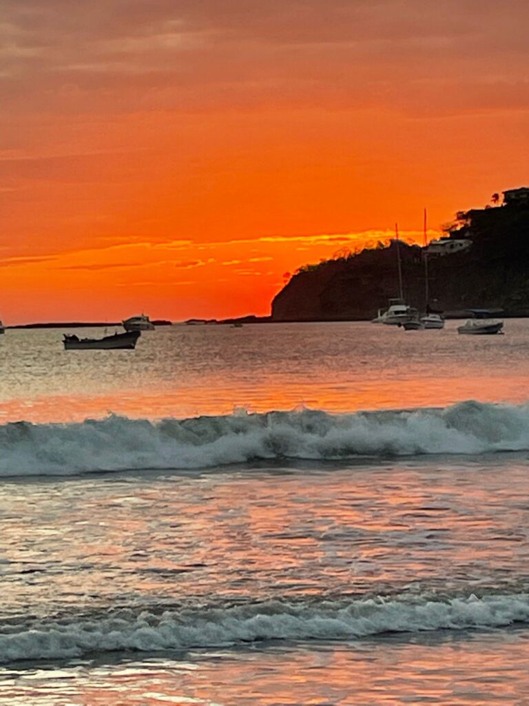 Bright orange sunsets at Playa San Juan del Sur in Nicaragua.

You can see the small waves coming in and a handful of boats in the bay.