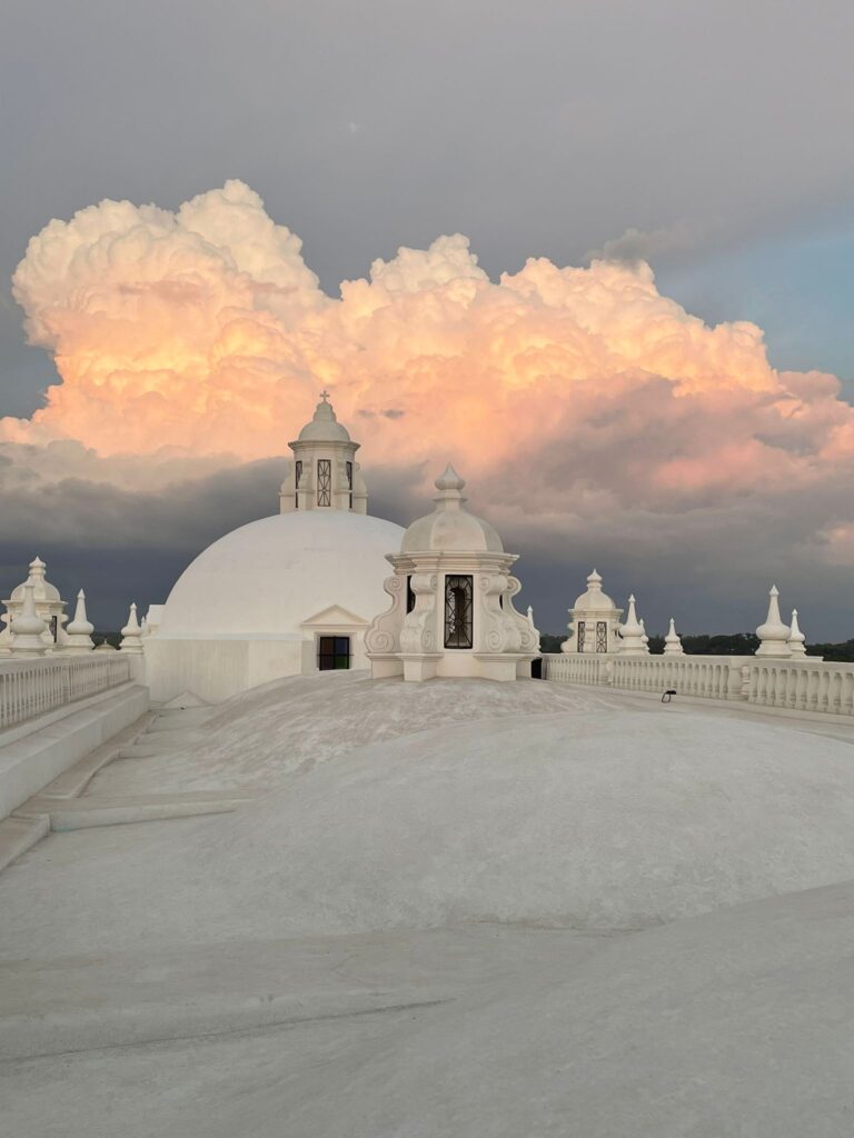 Orange clouds passing by the white rooftop of Leon Cathedral in Nicaragua