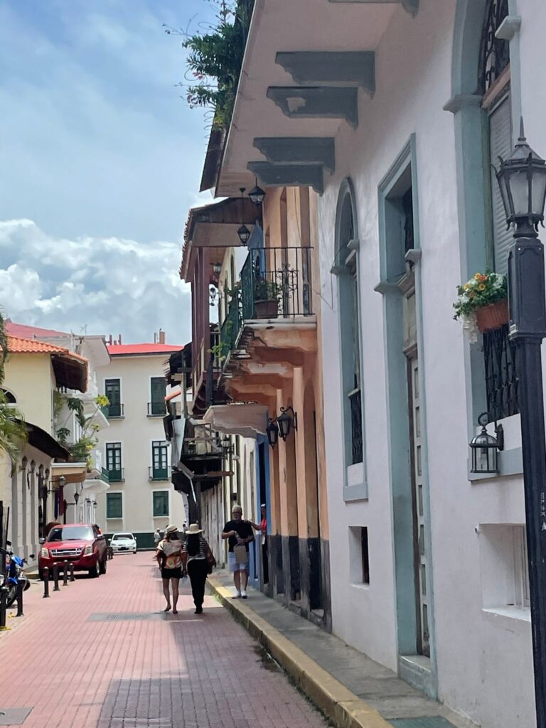 Colourful colonial buildings along the neatly-paved streets of Panama City's Casco Viejo neighbourhood. Two ladies are wearing Panama hats which the country is famous for