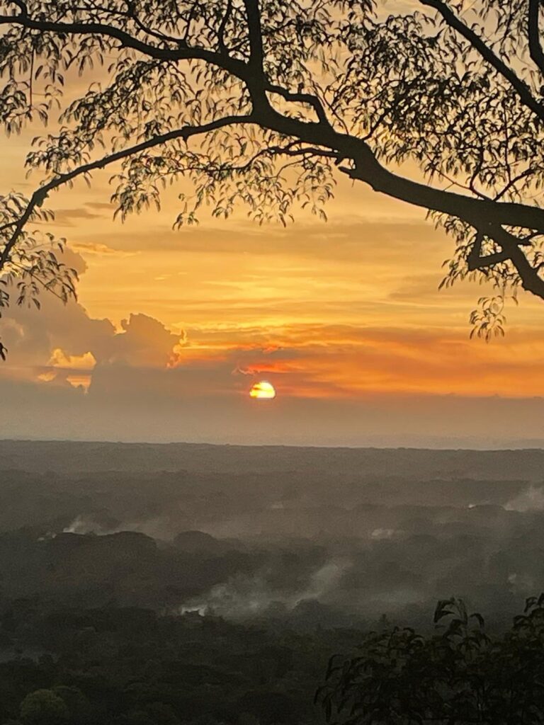 Sunset from Treehouse Nicaragua. The skies are bright orange with mist rising above the dark trees at the bottom