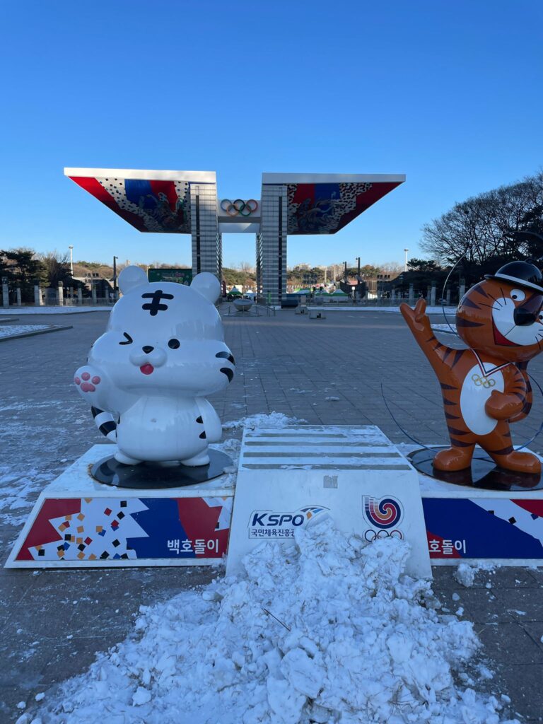 The World Peace Gate which marks the entrance to Seoul's Olympic Park. The five Olympic rings are shown clearly in the middle, whilst statues of a white cat (left) and 1988 Olympic mascot Hodori the tiger (right) stand in the foreground