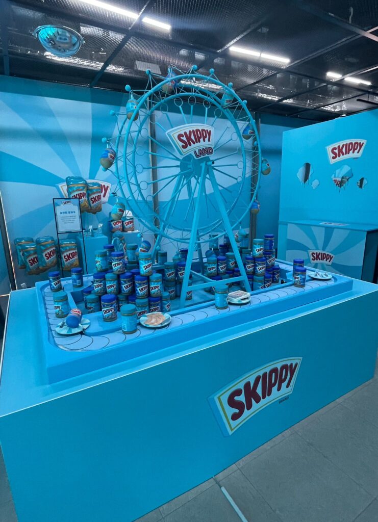 A conveyor belt at the Skippy building on the edge of Ikseon-dong Hanok Village. 

There are several jars of peanut butter beside a ferris wheel in the middle of the conveyor belt which is moving jars of Skippy (the peanut butter brand) around the wheel