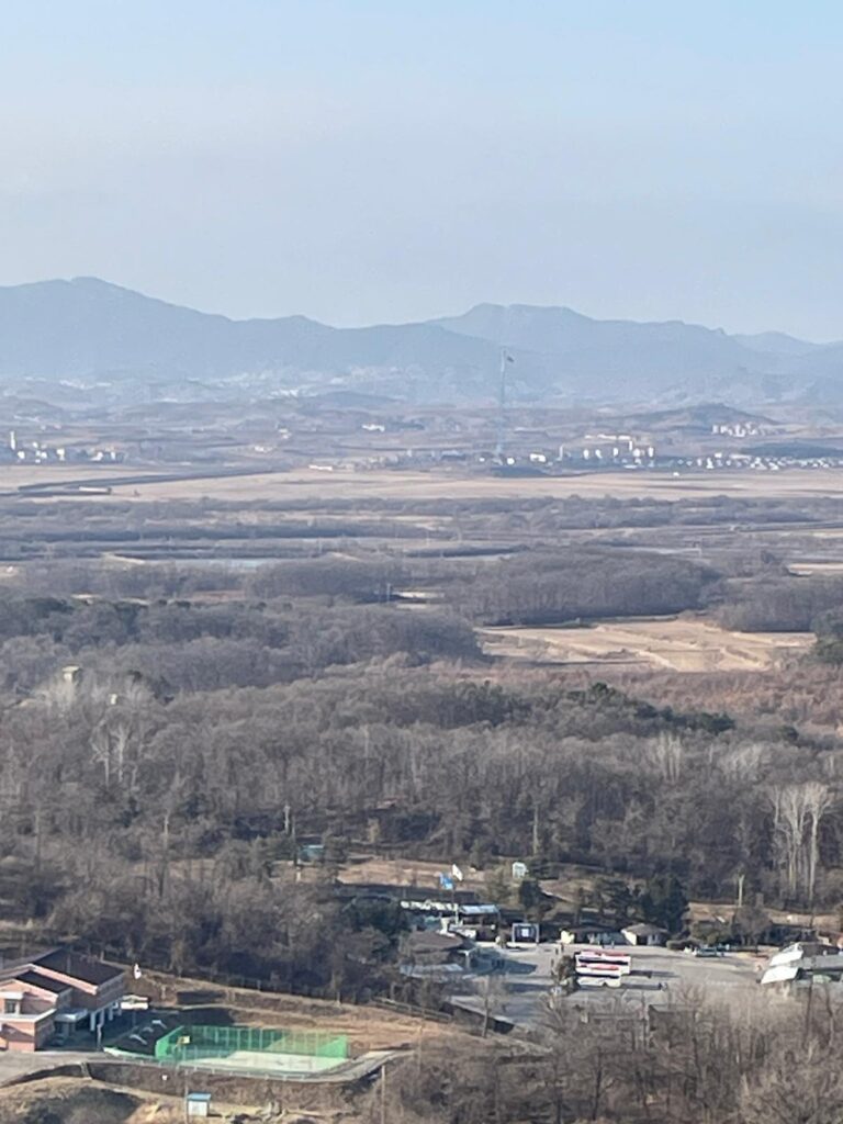 North Korea: as seen from Dora Observatory in the DMZ. The border is pretty much halfway down this photo. Everything in the top half is North Korea, including a flag just in front of the mountains at the back