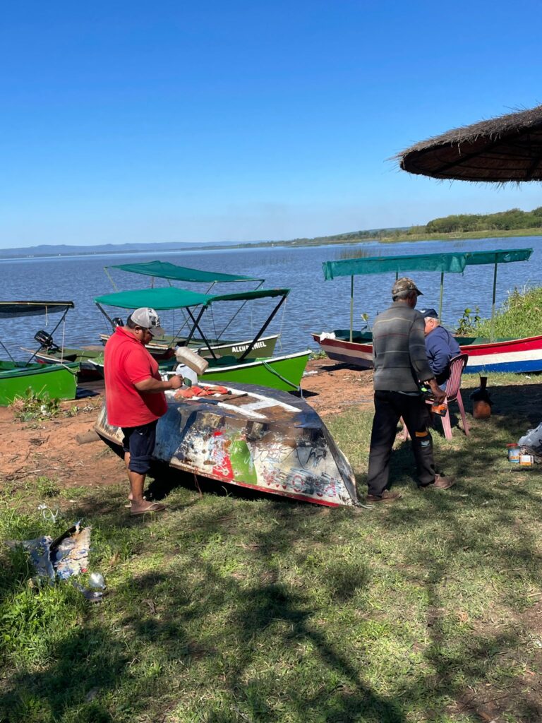 Three men in Aregua paint their boat ready to take out on Lake Ypacarai