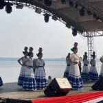 A group of dancers in traditional dress of white and blue skirts, with pots balanced on their heads. Location: San Bernardino, Paraguay