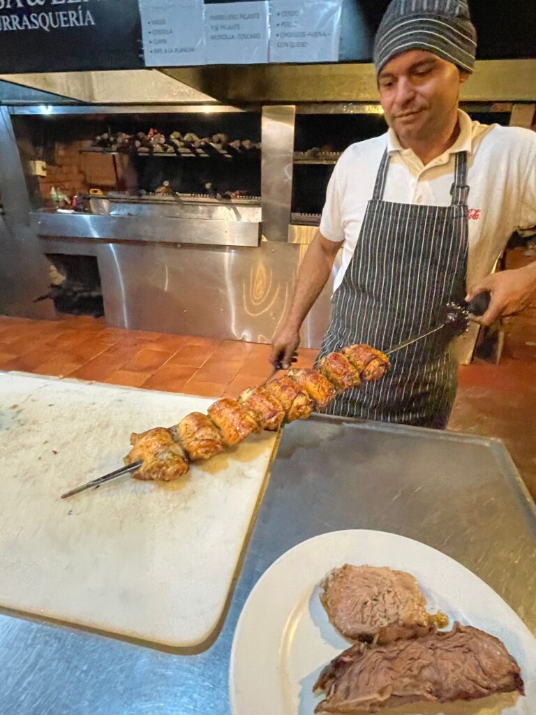 A waiter at Brasa y Leña with several chickens to serve up