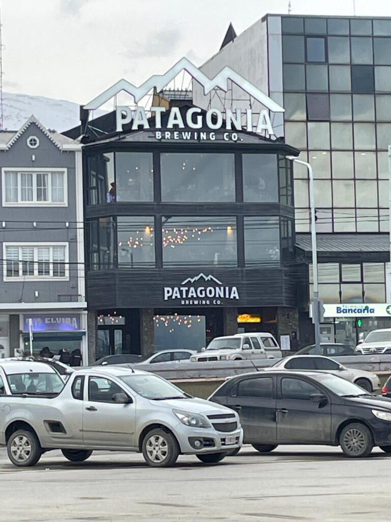 The Patagonia Brewing Company bar in Ushuaia, Argentina. It's a 3-story building with snowy mountains visible in the background. From inside you can see the Beagle Channel and more mountains