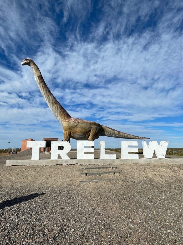 A dinosaur statue alongside a sign which says "Trelew" in the Patagonian city of the same name