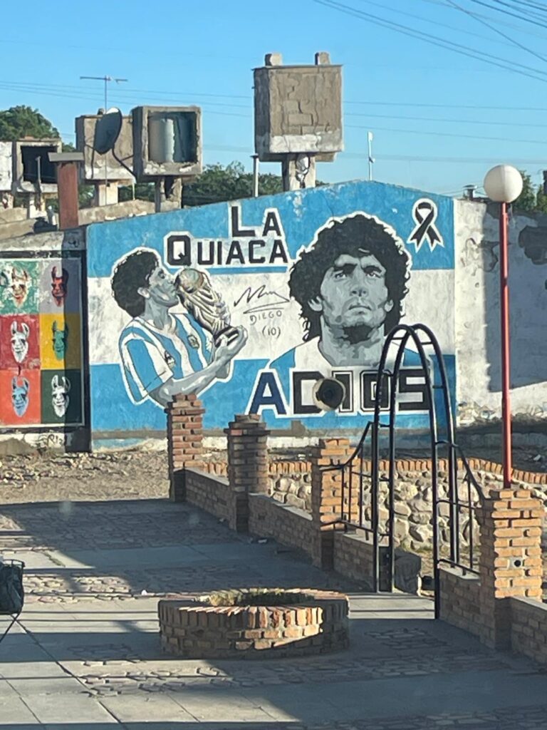 A mural paying tribute to Diego Maradona in the Argentinian border town of La Quiaca. It says "La Quiaca, Adios" with two images of Maradona including one where he lifts the World Cup