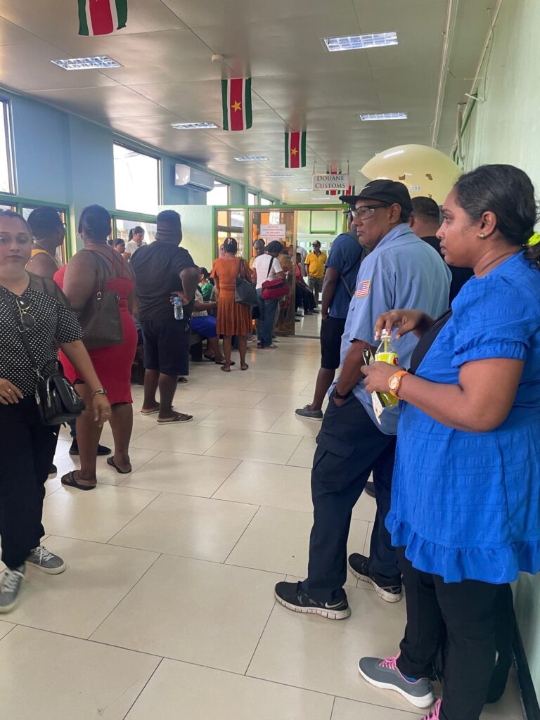 Several locals stand in a waiting room at the Suriname border in South Drain. This room is used for people to wait to receive their passports and tickets, which are given back after 20-30 minutes of waiting. Afterwards you proceed through immigration and customs