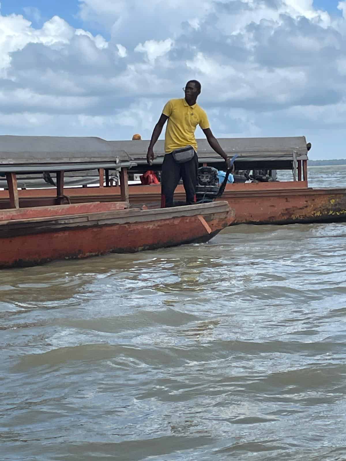 A man in a yellow shirt guiding his small wooden pirogue across the Maroni River between Suriname and French Guiana