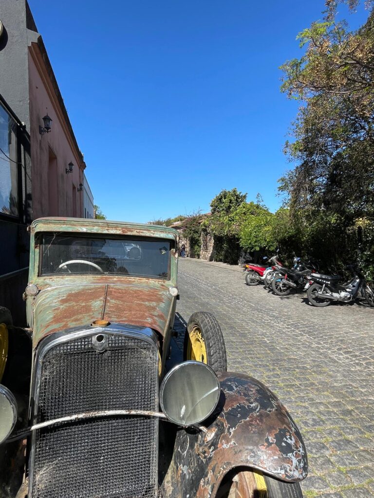 A vintage green car covered in brown rust. It is on the cobbled streets of Colonia del Sacramento in Uruguay