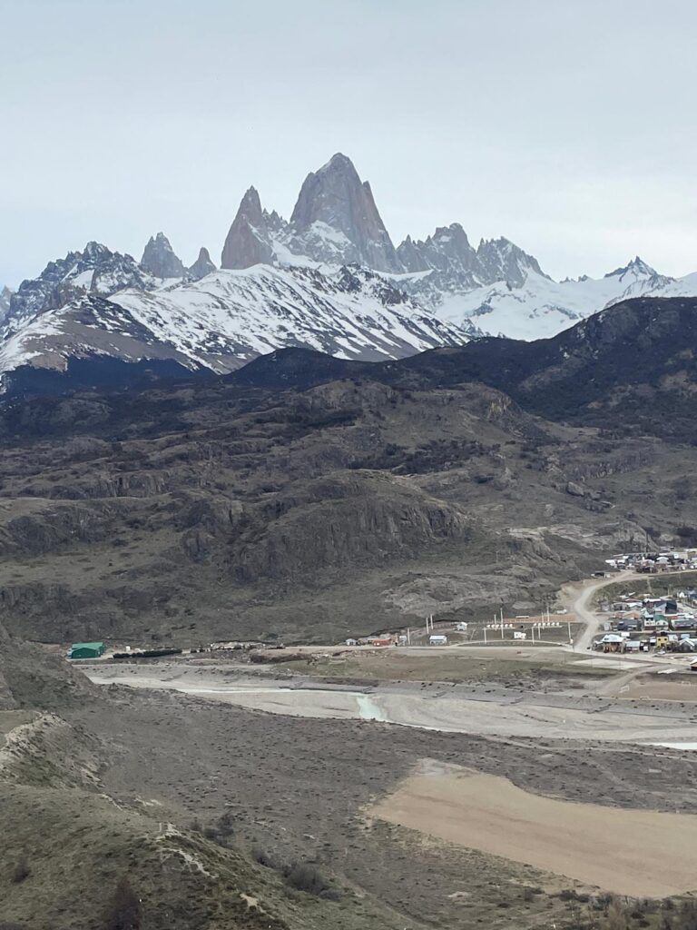 Icy mountain peaks tower over the small buildings below in El Chalten, Argentina