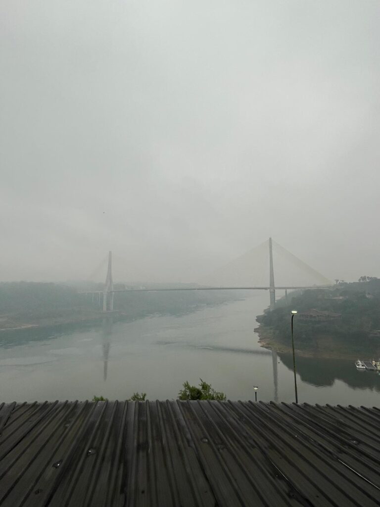 This gloomy picture shows a roof in the foreground and a bridge over a river in the distance.

The significance of this, is that it is the Triple Frontier border. The roof is in Argentina (where this photoo was taken from), the left side of the bridge is Paraguay and the right side is Brazil